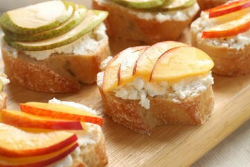 Delicious ricotta bruschettas with pears and apricots on wooden board, closeup