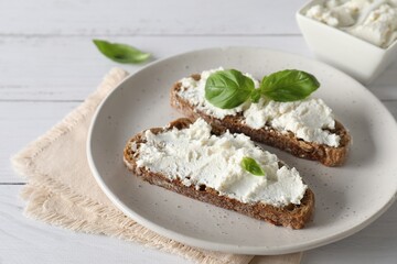 Bruschettas with ricotta cheese and basil on white wooden table, closeup