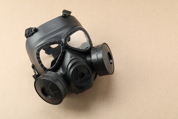 One respirator mask on beige background, top view and space for text. Safety equipment