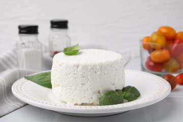 Fresh ricotta (cream cheese) and basil on light table, closeup