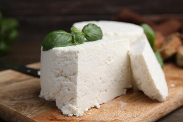 Fresh ricotta (cream cheese) and basil on wooden table, closeup