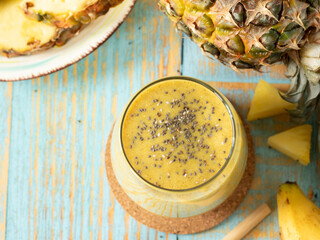 Yellow pineapple and banana smoothie with chia seeds on wooden table. Top view. Healthy tropical...
