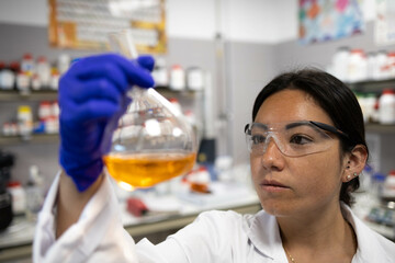 Woman scientist observing a liquid sample in a flask