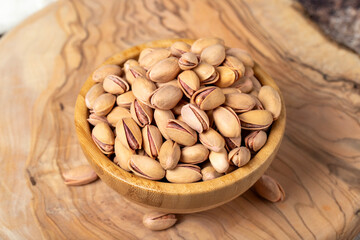 Pistachios on wooden background. Pistachios or pistacia vera in a bowl.