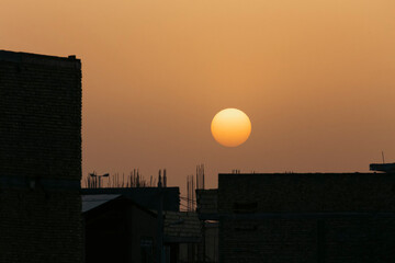 Sunset in the evening sky, silhouette of power transmission pylon and buildings