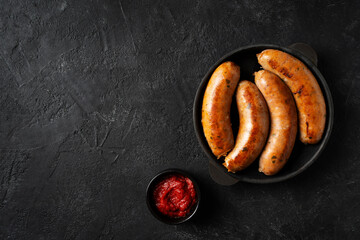 Bavarian sausage on black plate or pan, tomato sauce