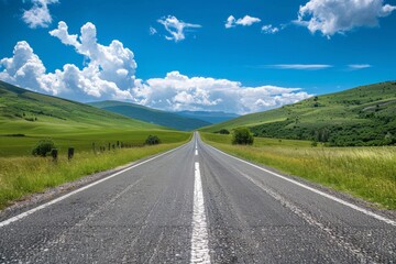 A long straight asphalt road stretches ahead through vibrant green hills under a blue sky with fluffy clouds
