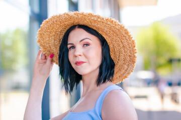 
Portrait of a beautiful woman in summer in the city with a straw hat. Summer stule outfit - casual dress. 
