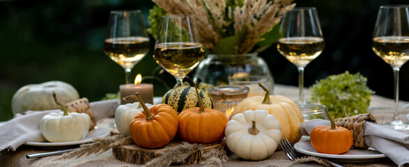 Simple craft elements, pumpkins as decoration, candles. Lunch outdoors in the garden. Cozy dinner table decor for an autumn event, countryside party, thanksgiving dinner or wedding banner