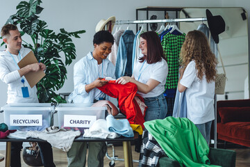 Concept of sustainable living, eco friendly planet saving, preserving textile pollution. Group of young volunteers sorting clothes for charity, recycling, donation. College university life, vintage