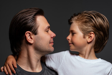 Father and son looking at each other portrait on dark background