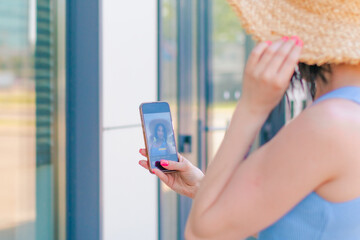 A woman takes a selfie while on holiday in summer. Clothes - casual, holiday summer dress with straw hat.   