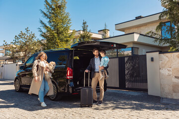 A young family with their son and dog and luggage going by car on vacation for the weekend