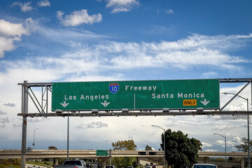 Obraz premium Street sign on Interstate 10 Freeway giving direction to Los Angeles and Santa Monica against blue sky with clouds