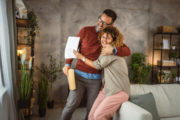 Obraz premium Happy couple read the good news in the post envelope letter and hug