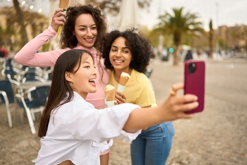 Young diverse friends taking selfie with ice cream outdoors