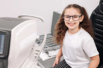 A female doctor holds special glasses to a patient for eye examination and lens selection in the...
