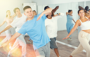 Group of energetic different people learning dance at dance class