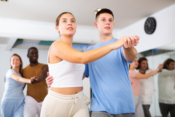 Woman and man practicing bachata dance moves in pair during group class