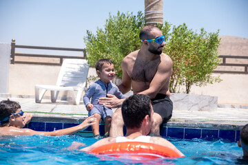 Relatives of different ages are enjoying themselves in the swimming pool, having a great time together and supporting each other to make the most of their vacation