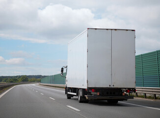 White Delivery Truck Driving on Highway with Green Landscape Background