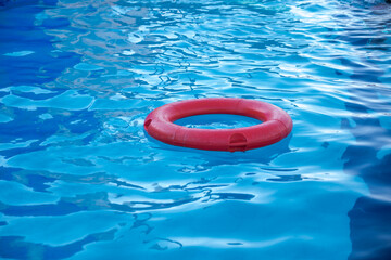  A red lifebuoy floating in the pool, creating a serene and safe environment. The water is clear and blue under the bright sun