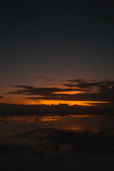 A serene beach sunset with a vibrant sky reflecting on the wet sand. The peaceful atmosphere captures the natural beauty and tranquility of the evening by the sea.