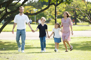 Obraz premium Happy family relaxing together at the park, caucasian family with father, mother, and children walking at the park.