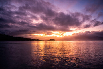 Breathtaking sunrise over Pacific Ocean in Tahiti French Polynesia with puffy clouds and reflection on the water beckoning a new day