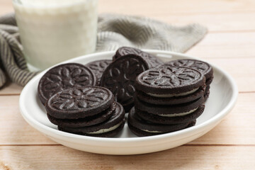 Plate with tasty sandwich cookies on light wooden table, closeup