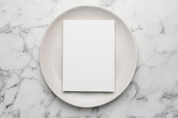 Empty menu and plate on white marble table, top view. Mockup for design