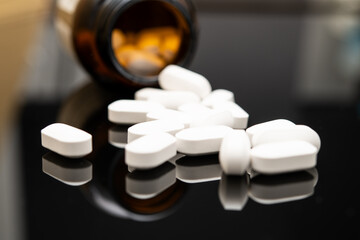 Close-Up Image of White Opioid Pills Spilled from Prescription Bottle on Glossy Surface