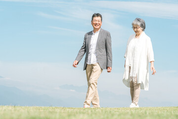 公園・旅行先を話しながら歩く高齢者夫婦（シニア・男女）
