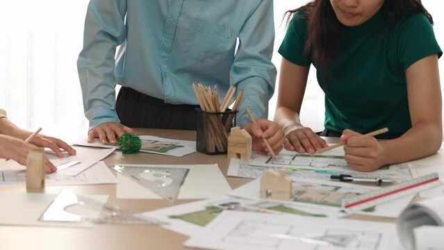 A video of architect use measurement tools and pencil to measure blueprint. Architect design house construction on a table at studio, with architectural plan scattered around. Focus hand. Delineation.