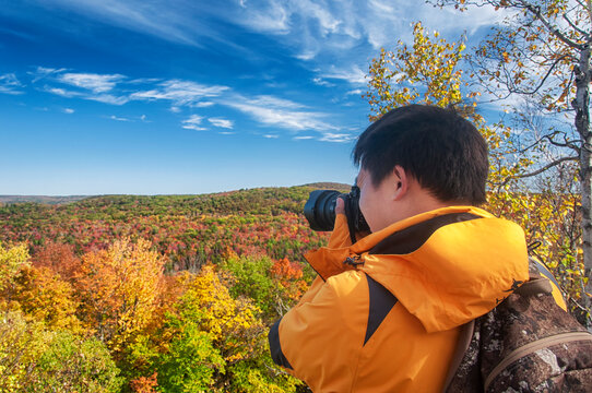 chinese man photographing fall foliage in new england