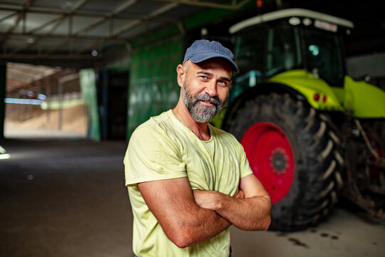 Confident male farmer with arms crossed standing in tractor shed