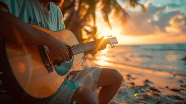A man is playing a guitar on a beach at sunset