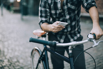 Obraz premium Man using smartphone while riding bicycle in city