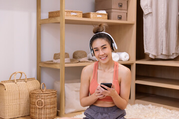 Happy asian woman use headphones listen to music from smartphone outdoor sitting on cozy sofa in living room at home. Music mental therapist for relaxation woman. Leisure cheerful wellness woman