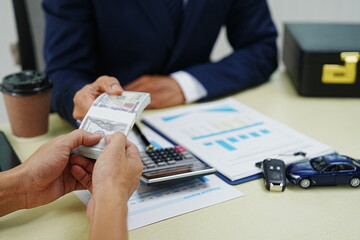 A businessman signs a contract for car insurance in an office. Holding a pen, he finalizes the agreement with the agent. This ensures protection and security for his new vehicle.