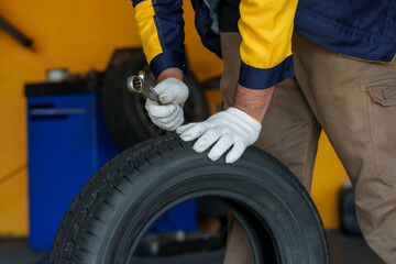 Fototapeta premium Close-up of mechanic's hands working on a tire with a wrench in a garage. Focus on detailed tool usage and maintenance. Professional auto repair setting with emphasis on hands-on work.