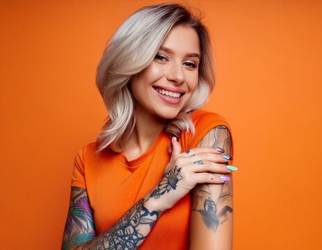 Young woman with arm tattoos isolated on orange background blonde bob orange shirt cool edgy vibe
