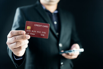 Businessman showing a red credit or debit card and holding phone to make a payment. An internet wireless online technology and online shopping concept idea