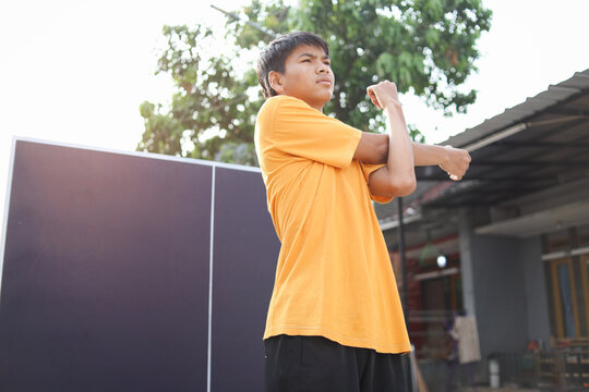 Potrait Of Confident Young Asian Guy Stretching Arms Before Playing Ping Pong Sport.