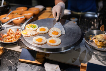 Fried eggs and delicious menu items for breakfast in the hotel There is a chef scooping food with a spatula and serving it to people who place orders with the chef. It tastes delicious.