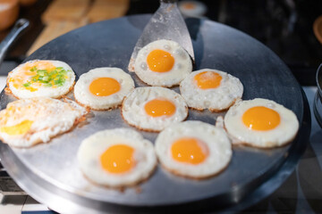 A close-up menu of fried eggs in a pan, delicious for breakfast and dinner in the hotel. The chef is scooping it up with a spatula and serving it to people who place orders with the chef.