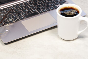 
淹れたての美味しいコーヒーを飲みながら、ノートパソコンでデスクワークをしているイメージ	
