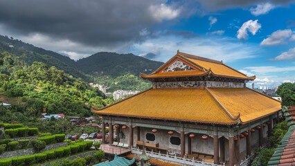 Details of the architecture of the Chinese temple. The tiled roof of the pagoda is decorated with ornaments. There are rows of lanterns along the curved edges. Trimming bushes on the terraces 