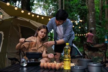 close up and selective focus of young asian woman sitting grilled meat in pan  picnic gas in the night camping.