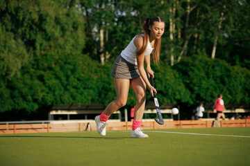 Obraz premium girl hockey player plays field hockey on a sunny day, the hockey player hits the ball with a stick
